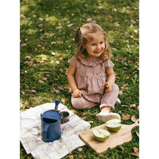 Kleines Mädchen in altrosa Rüschencollier T-Shirt auf Gras lachend