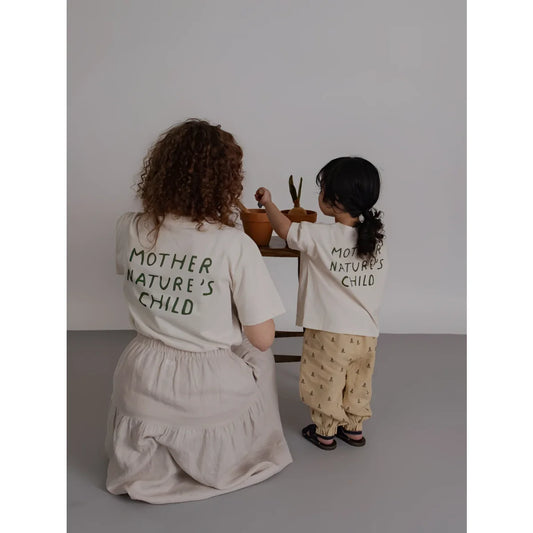 Rückseite des Mother Nature’s Child T-Shirts in Off-White mit grüner Schrift