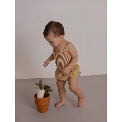 Baby in Tank Bodysuit Copper Stripes neben Terrakottatopf mit Pflanze