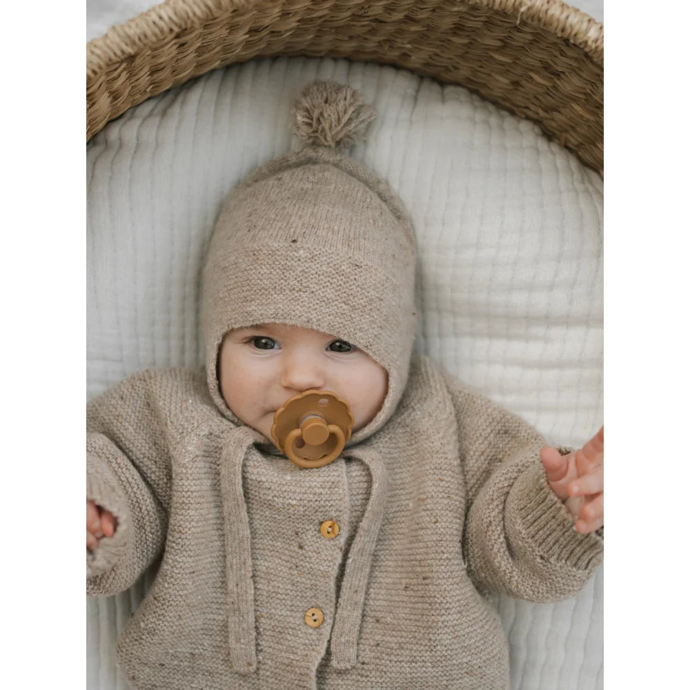 Süßes Baby mit beige gestricktem Tassel Wool Hat und Cardigan mit Schnuller