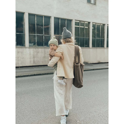 Erwachsene trägt ein Kind auf der Straße mit Teddy Mom Bag in Braun