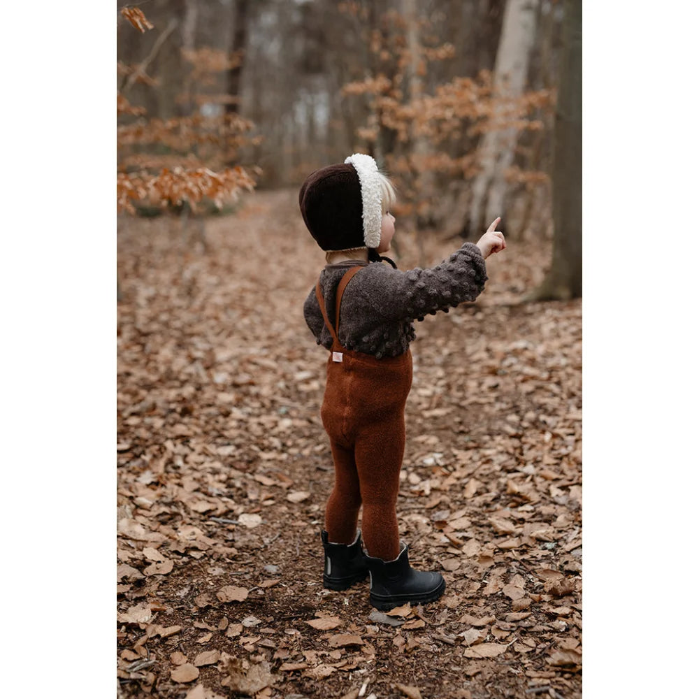 Kind in Mütze und Jacke im Wald mit Teddy Warmy Strumpfhose in Zimt