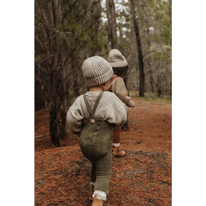 Kind in Latzhose und Mütze auf Waldweg mit Teddy Warmy Strumpfhose in Olive