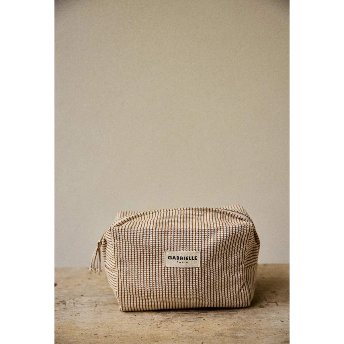 Beige weiße gestreifte toilettentasche aus baumwolle mit gewebter struktur und label gabrielle paris für ökologische baby- & kinderprodukte