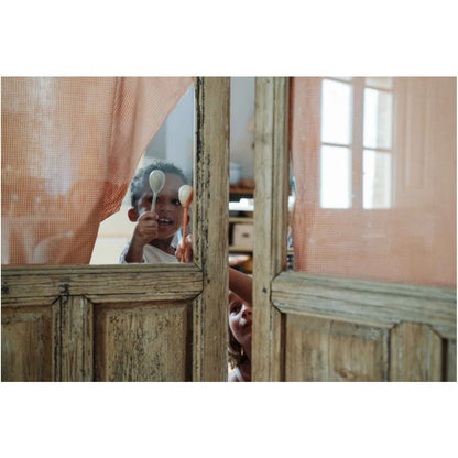 Kind hält zwei helle Holzlöffel als spielerische Instrumente für Twin-souls Puppets