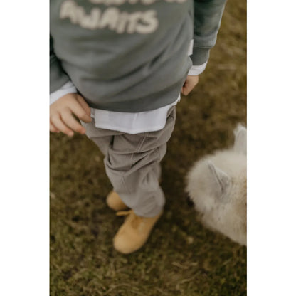 Graues oversized Sweatshirt mit Abenteuer wartet Text und hellbraune Wildleder-Loafers