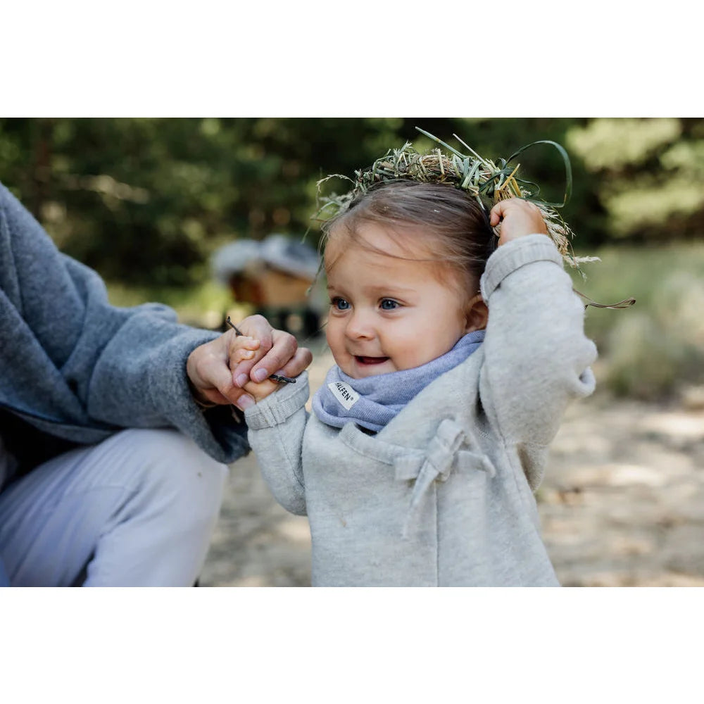 Baby mit Blumenkranz und hellfarbener Kleidung im Walk-Jäckchen zum Binden natur