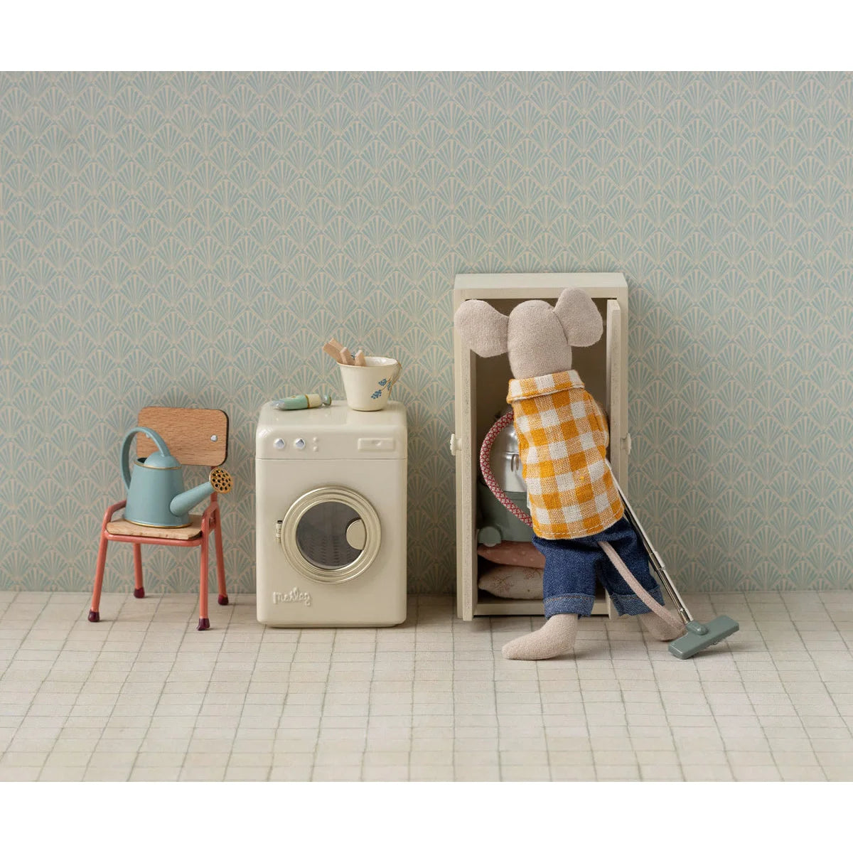 Mini Maus in Karohemd saugt Waschmaschine-Kabinettaus rein