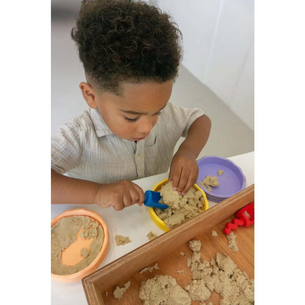 Junge spielt mit Kinetic Sand und Spielzeug, ideal für Little Botanic Label Produkte