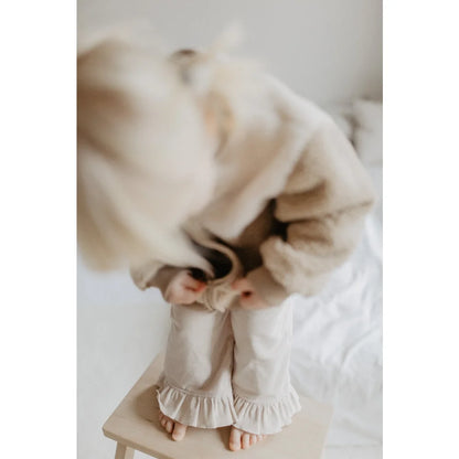 Kind eines Kindes in cremfarbener Longsleeve und Rüschenhose aus Weite Cordhose mit Rüschensaum cappuccino