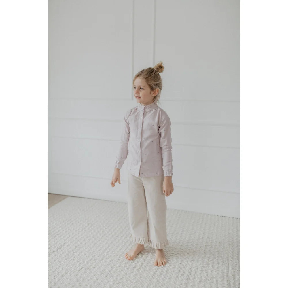 Junge Frau trägt weite cappuccino Cordhose mit Rüschensaum und helles Hemd