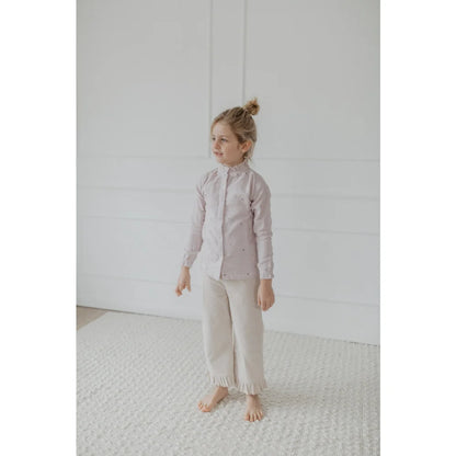 Junge Frau trägt weite cappuccino Cordhose mit Rüschensaum und helles Hemd