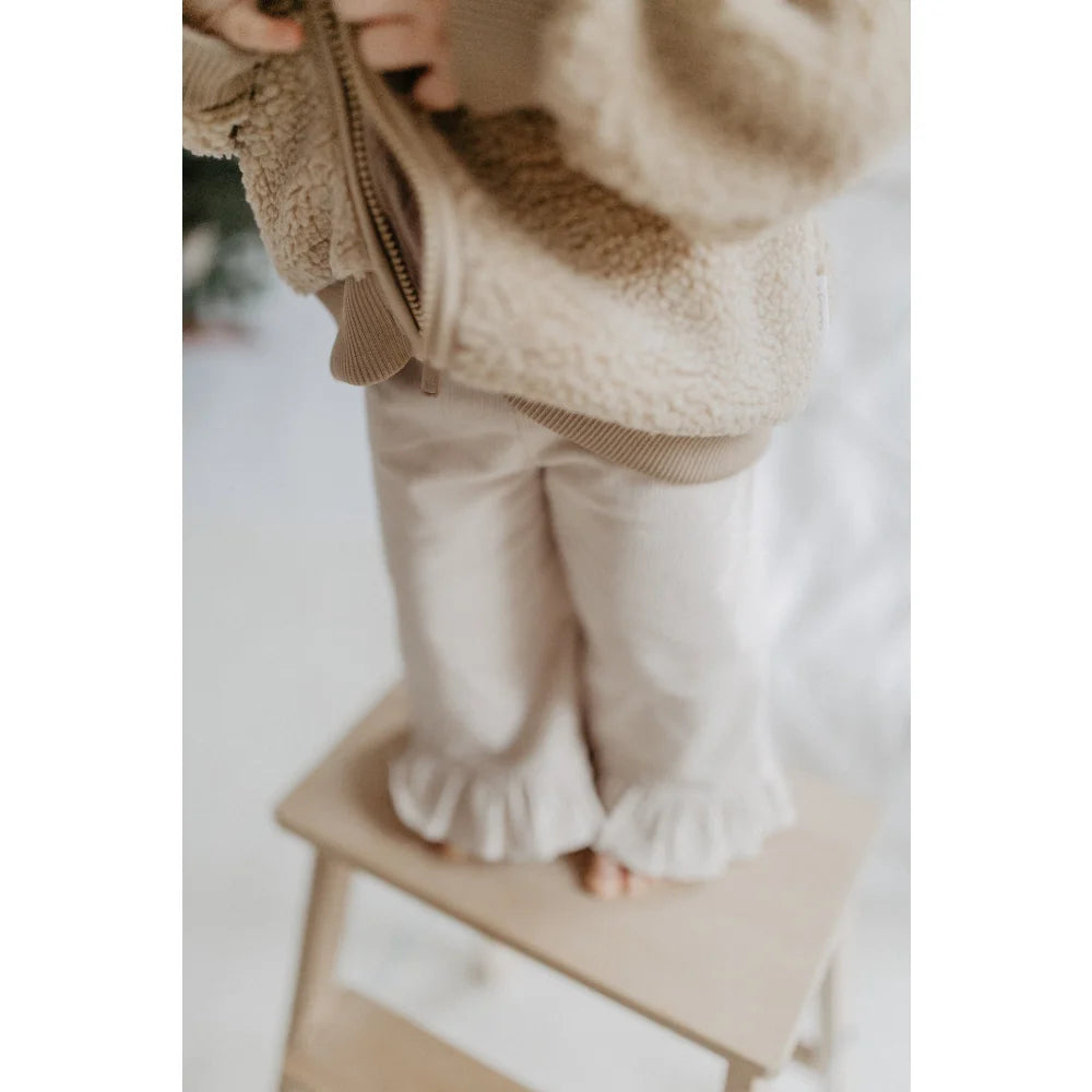 Kindermantel in neutral Tönen mit Rüschen an den Hosen, perfekt für den Winter