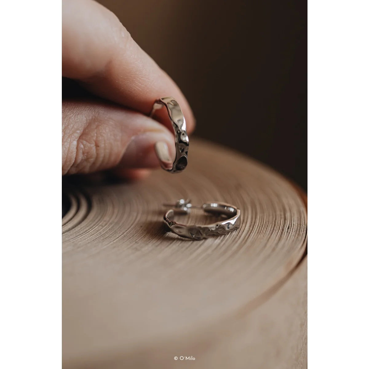 Hand hält Odelia Kreolen Silberohrringe mit hammered Finish