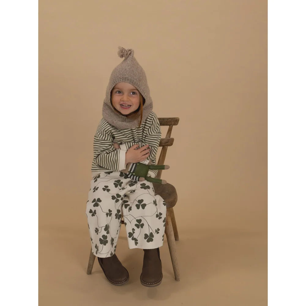 Junge mädchen trägt Oatmeal Woll-Balaclava mit Bommel, gestreiftem Shirt und Klee-Hose