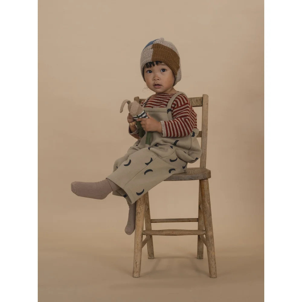 Junge sitzt auf Holzstuhl in Wool Jumper Paprika Streifen mit Plüschtier