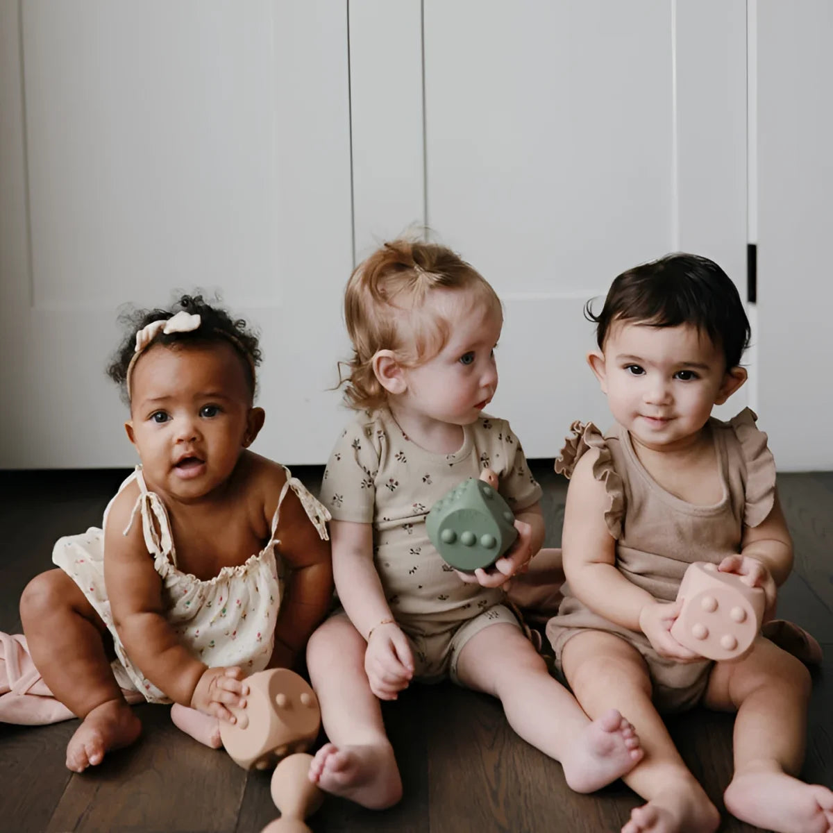 Drei Babys halten Spielzeugwürfel Würfel Plop-it Spielzeug Cambridge Blue Shifting Sand