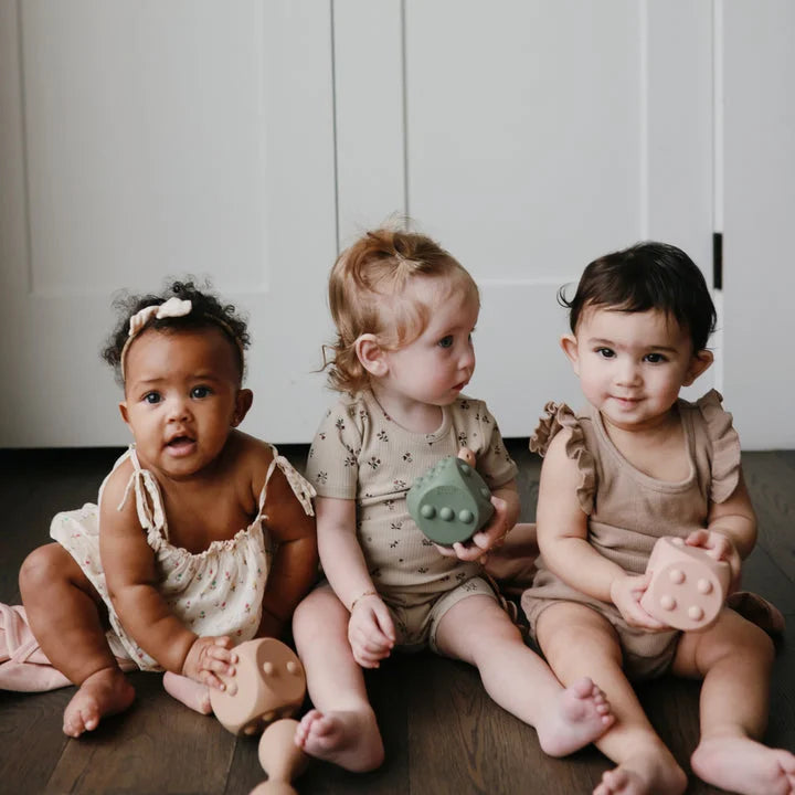 Drei Babys halten Spielzeugwürfel Würfel Plop-it Spielzeug Cambridge Blue Shifting Sand